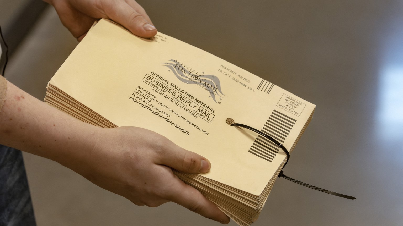 A poll worker holds a stack of ballot envelopes. 