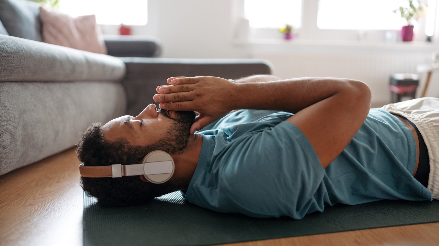 A man laying on the floor in a relaxed pose listening to headphones. 