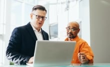 Two people looking at laptop screen and talking