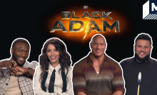 Dwayne Johnson, Aldis Hodge, Sarah Shahi and Mohammed Amer smiling in front of the Black Adam Logo