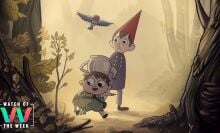 A young boy in green overalls with a teakettle on his head and a teenage boy in a blue cloak and conical red hat walk through the woods. A bluebird flies with them, and the younger boy holds a frog under his arm.