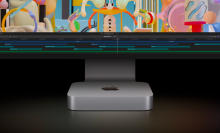 an m2 apple mac mini beneath an imac with a colorful display against a dark, shadowy background