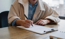 person writing on resume at desk