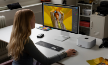 a woman sitting at a workstation using a display hooked up to a mac studio