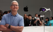 Apple CEO Tim Cook posing next to the Vision Pro headset