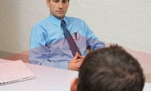 Man wearing the Mini Body Camera while sitting in front of another person.