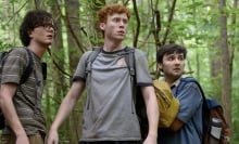 Three young men hike through the forest.