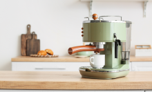 Modern coffee machine with cup on counter in kitchen