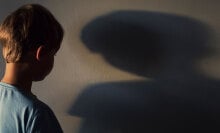 A boy looks at his shadow on a wall.