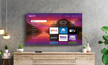 Hanging TV with streaming apps and Roku smart TV platform on screen with furniture and plants in peripherals