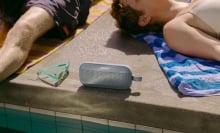 Person laying next to Bose Bluetooth speaker by the pool.