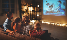 family mother father and children watching projector, TV, movies with popcorn in the evening   at home 