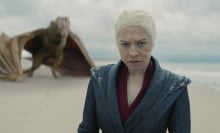 Rhaenyra Targaryen stands on a beach, with her yellow dragon Syrax behind her.