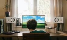 boy sitting in front of desktop computer with external speakers