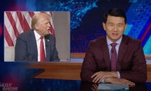 A man in a suit sits behind a talk show desk. In the top-right corner is an image of another man.