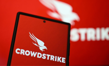 The CrowdStrike logo on phone screen is displayed in front of CrowdStrike logo on laptop screen.