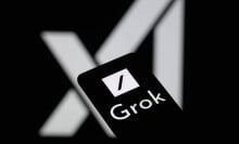 The Grok logo is being displayed on a smartphone with the X AI icon visible in the background.