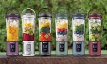 a lineup of ninja portable blenders that are various colored and filled with various smoothie ingredients, sitting in each blender unblended