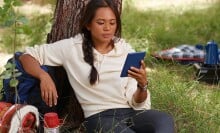 A girl sits outside and reads on her Amazon Kindle 