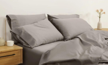 Bed with gray bedding and nightstands in peripheral view