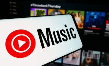 In this photo illustration, a mobile phone with the logo of American music streaming service YouTube Music is seen in front of business website. 