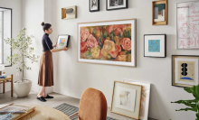 woman hanging art on wall