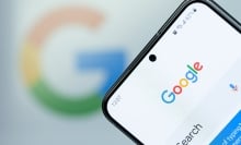 Google search app on smartphone screen close up with blurred logo background.