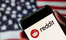 A phone displaying the Reddit logo in front of an American flag.