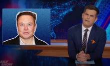 A man in a suit sits behind a talk show desk. In the top-left is an image of another man.