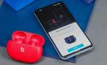 A pair of Beats Studio Buds on a table next to a phone