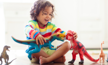 small child laughing and playing with dinosaur toys 