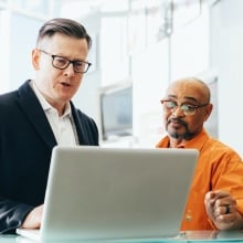 Two people looking at laptop screen and talking