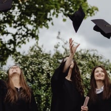 Three people throwing their graduation cap to the sky.