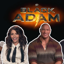 Dwayne Johnson, Aldis Hodge, Sarah Shahi and Mohammed Amer smiling in front of the Black Adam Logo