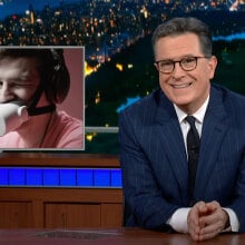 A man sitting behind a talk show desk is seen with another image next to him of a man wearing a gadget over his mouth and winking.