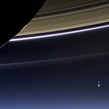 An arrow pointing to the Earth (a blue dot) with Saturn's rings in the foreground.