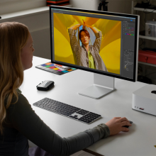 a woman sitting at a workstation using a display hooked up to a mac studio