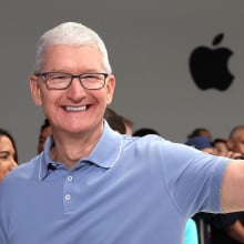 Tim Cook in front of an Apple logo flashing a peace sign