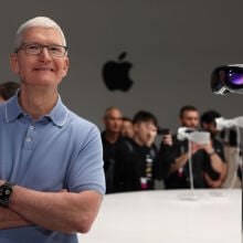 Apple CEO Tim Cook posing next to the Vision Pro headset