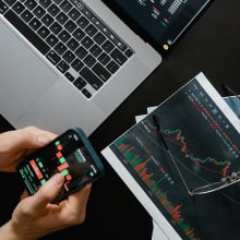 man holding a smartphone looking at investment charts