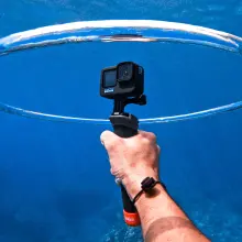 a right hand holds a gopro in a ring of air underwater