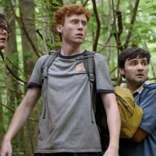 Three young men hike through the forest.