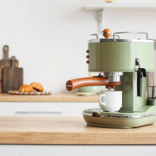 Modern coffee machine with cup on counter in kitchen