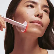 Woman uses a Solawave red light therapy wand