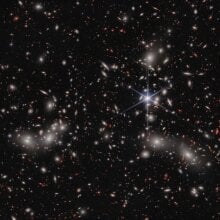 The galaxy group Pandora’s Cluster sits in front of a cosmic background brimming with deep space galaxies.