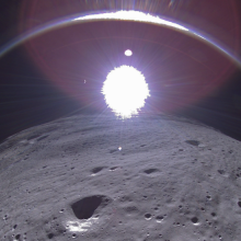 A transmission from Intuitive Machines' Odysseus moon lander showing the crescent Earth near the top of the image, to the left of center.