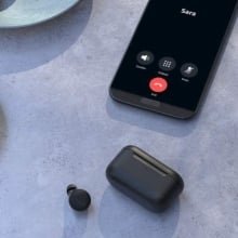 Amazon Echo Buds sitting on a table with a smartphone