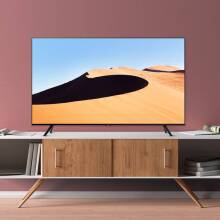 Samsung 4K TV with sand dune screensaver sitting on TV stand with pink wall in background