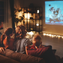 family mother father and children watching projector, TV, movies with popcorn in the evening   at home 