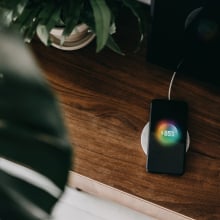 Directly above shot of a smartphone getting charged with wireless charging device on a cabinet in the living room